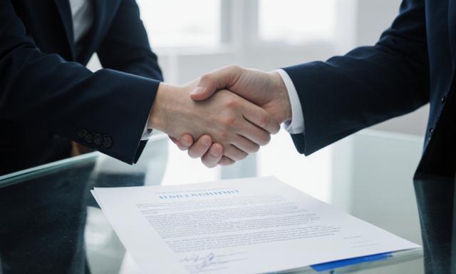 Stretta di mano sopra un contratto strutturato in un ufficio moderno